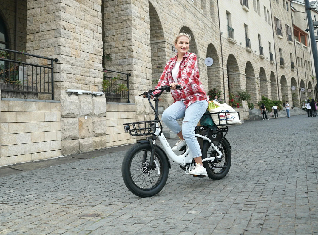 Frau fährt mit dem DYU C9 Klapp-E-Bike über Kopfsteinpflaster in einer Einkaufsstraße