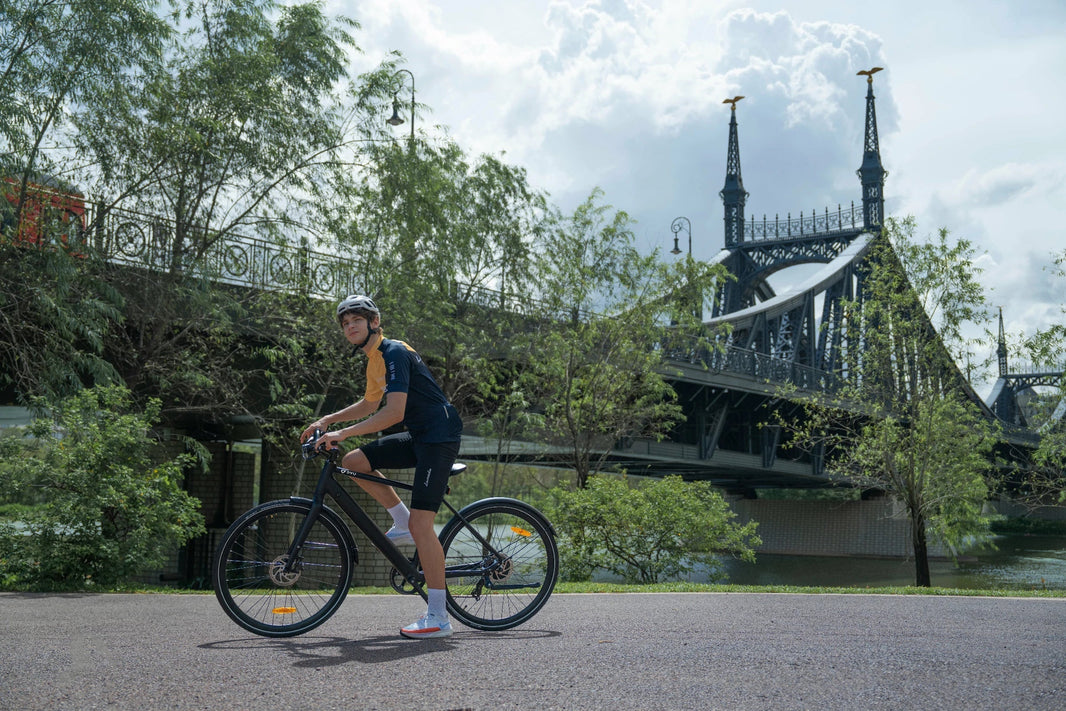 Mann steht mit dem DYU Stroll 1 E-Bike auf einer Flussbruecke